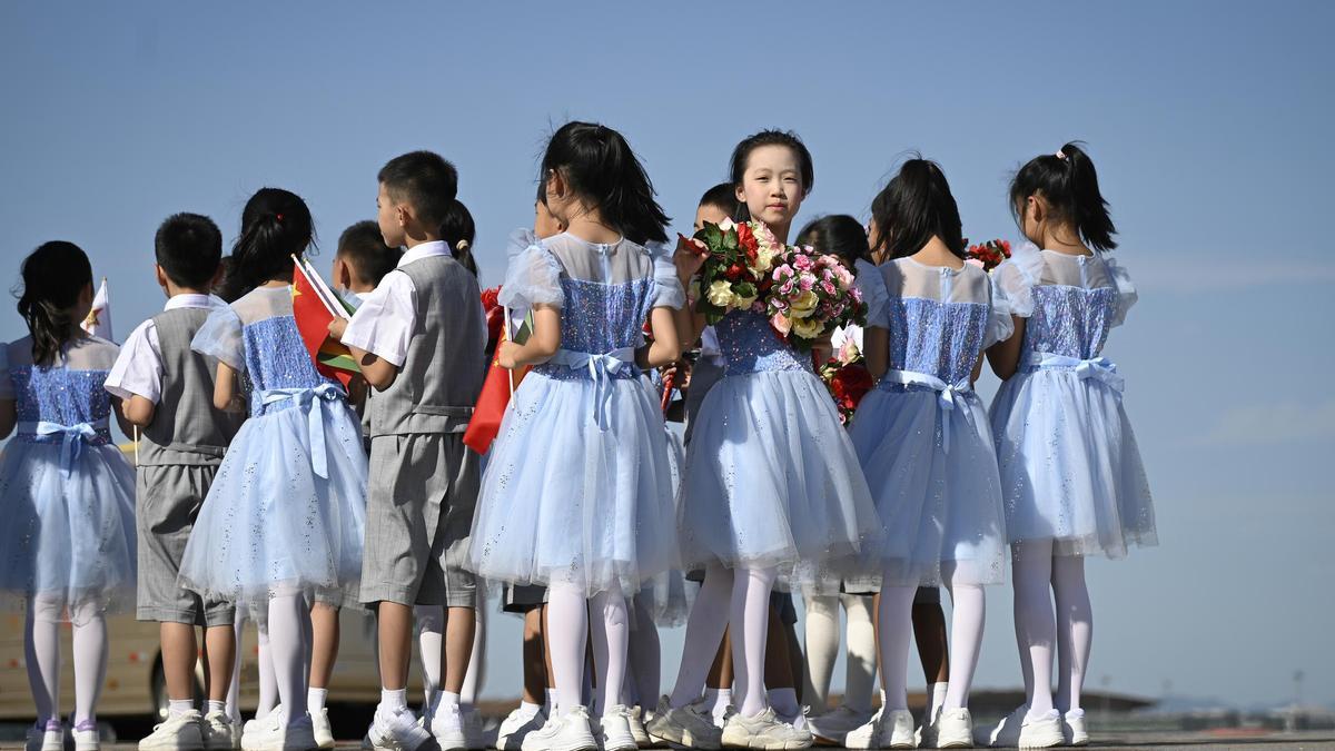 Niños chinos con banderas y flores, en el Aeropuerto Internacional de Pekín durante un acto oficial.