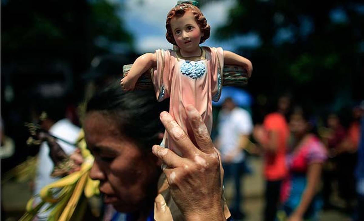 Una dona porta una estàtua del nen Jesús abans d’assistir a la missa de diumenge de Rams, a la catedral metropolitana de Managua (Nicaragua).