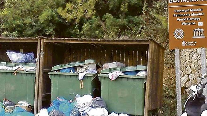 Un contenedor lleno de basuras, al lado de un cartel de la Serra.