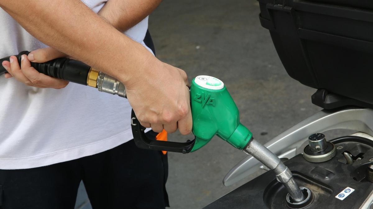 Un empleado de una gasolinera rellena el depósito de una moto, en Barcelona.