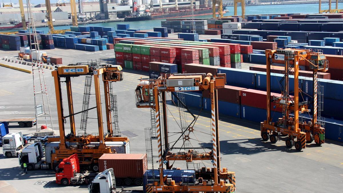 Unes grues especials transportant contenidors a la zona de càrrega de mercaderies del Port de Barcelona
