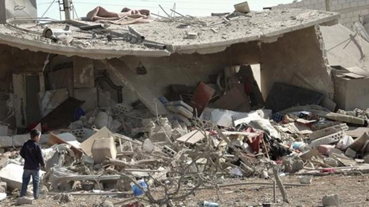 Un niño observa los restos de una casa destrozada en Homs tras un atentado con coche bomba, este lunes.