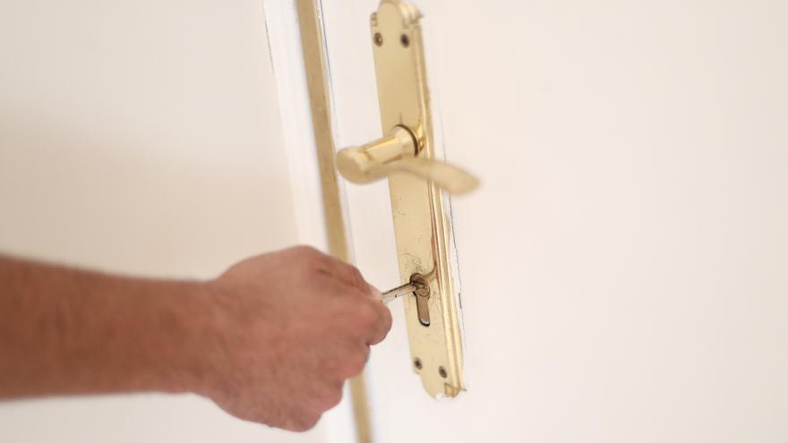 Un hombre introduce una llave en la cerradura de la puerta de su nueva vivienda.