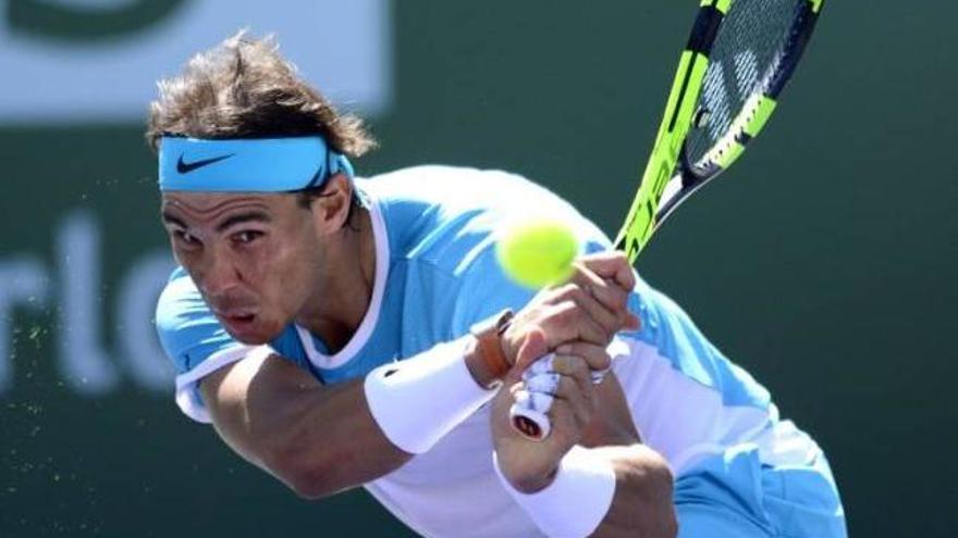 Nadal observa la pelota tras golper de revés en su partido contra Djokovic.