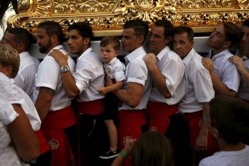 Men in traditional costumes carry a statue of the El Carmen Virgin, on its way to be carried into the sea, during a procession in Malaga