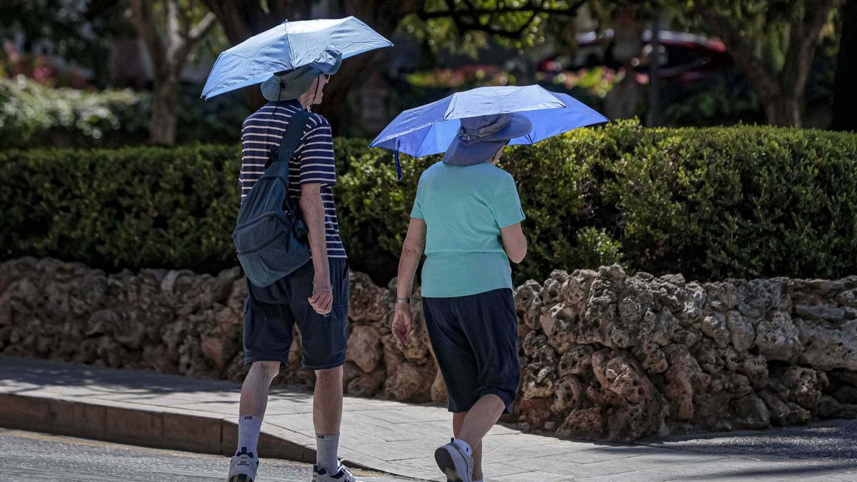 Dos turistas, en el centro de Palma, se protegen ante las altas temperaturas de este agosto.
