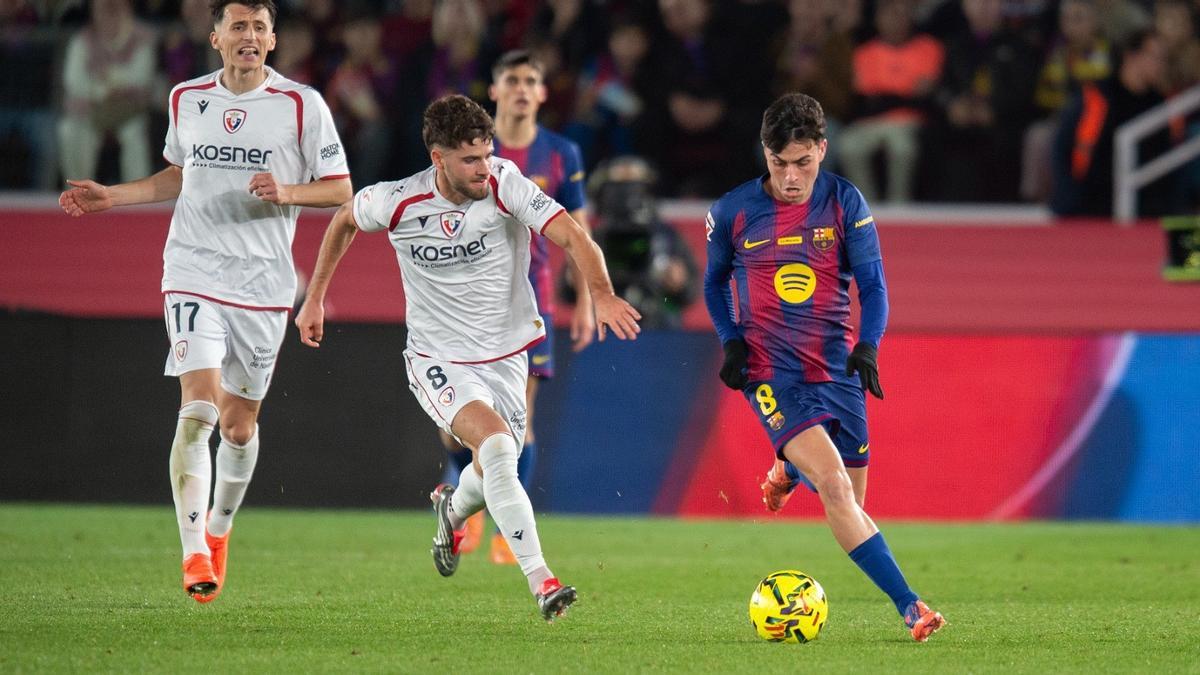 Pedri conduce un balón con Iker Muñoz persiguiéndole.