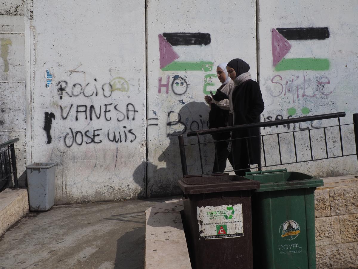 Dos mujeres caminan junto al muro de Cisjordania en el puesto de control de Belén.