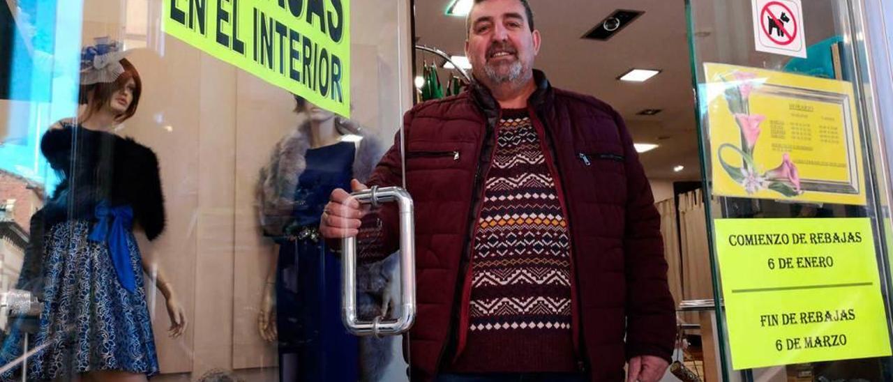 Tomás García, en su tienda, con un cartel de rebajas.