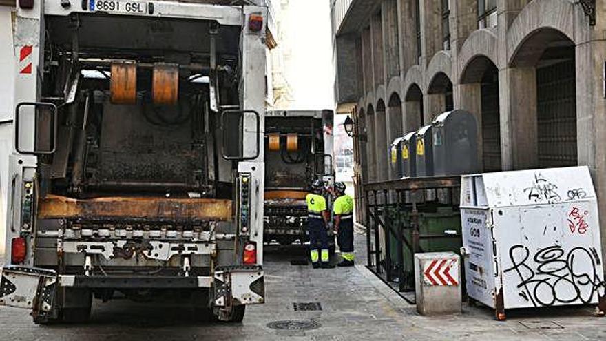 Dos operarios de la recogida de basura con dos camiones en una calle de la Ciudad Vieja.