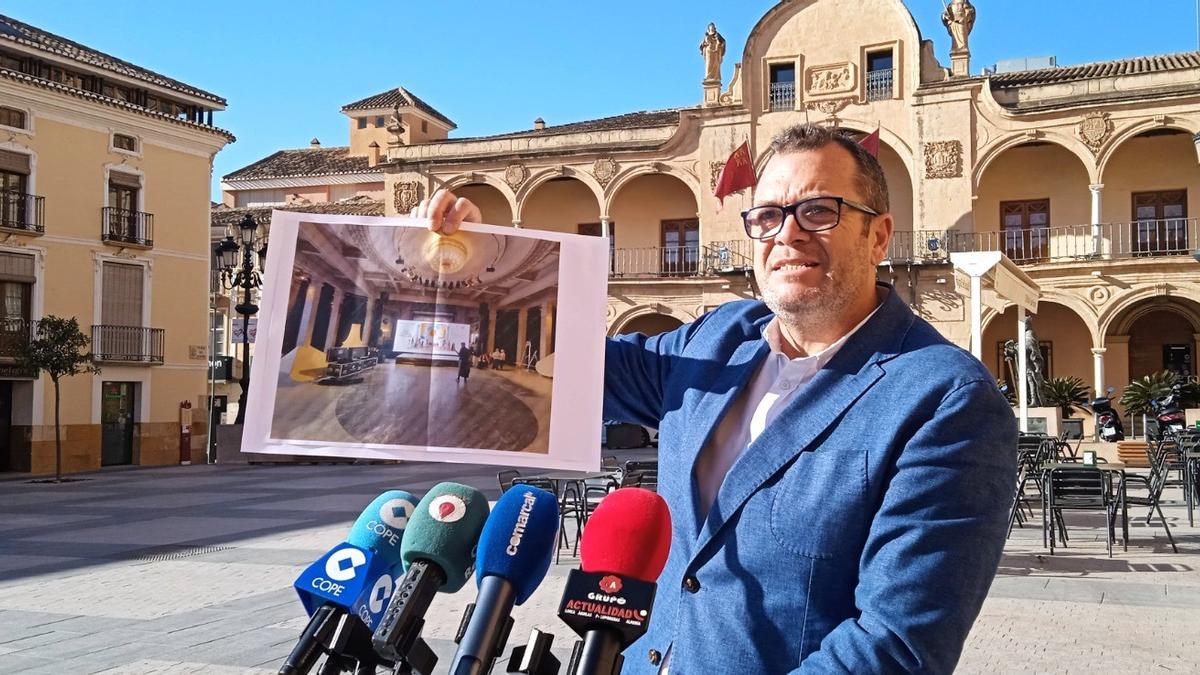 El edil popular Juan Miguel Bayonas López con una fotografía del lugar donde estaba previsto que se celebrara el acto promocional, en Madrid.