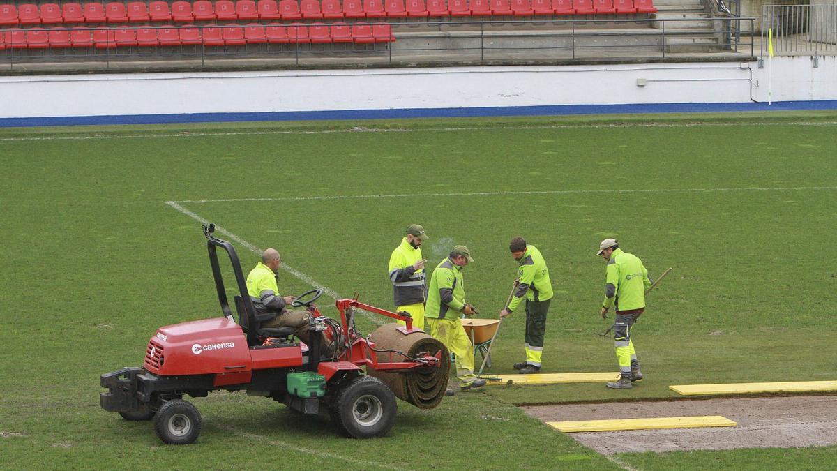 Operarios sustituyen un tramo deteriorado del césped en el estadio de O Couto.