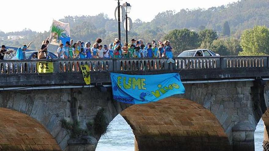 Participantes en el campamento de Greenpeace cuelgan una pancarta en el puente de piedra. / laura del pozo