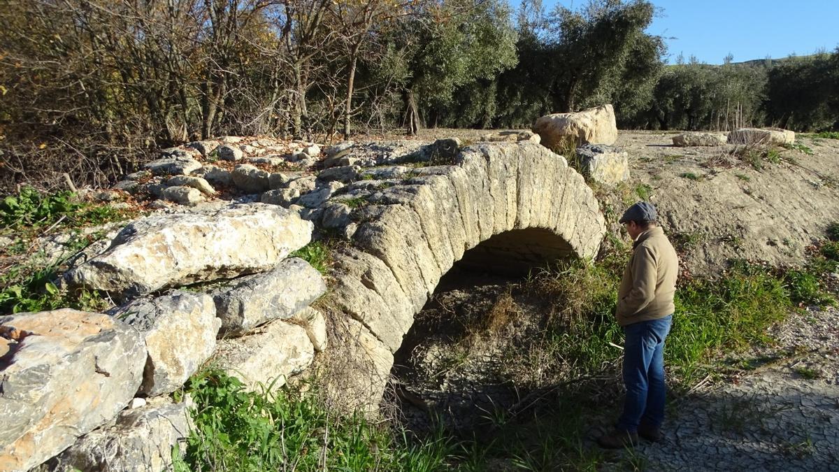 Un hombre observa el puente romano de Fontalba, de un solo ojo.