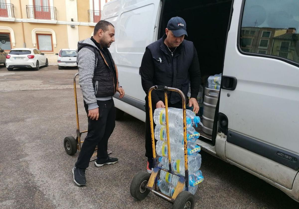 Dos empleados de una empresa descargan garrafas de agua para abastecer a comercios de la ciudad. | M. J. C.