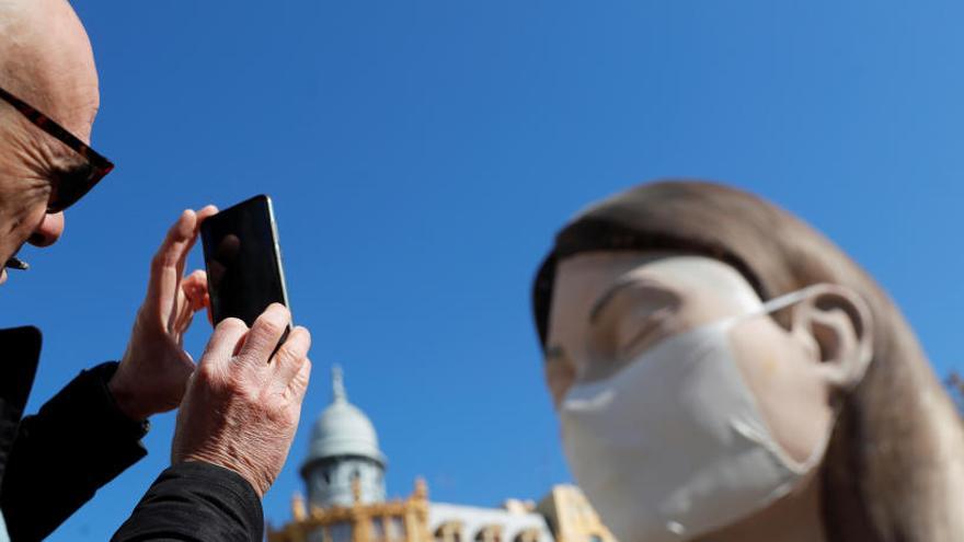 Un hombre fotografía a un ninot con mascarilla en Valencia.