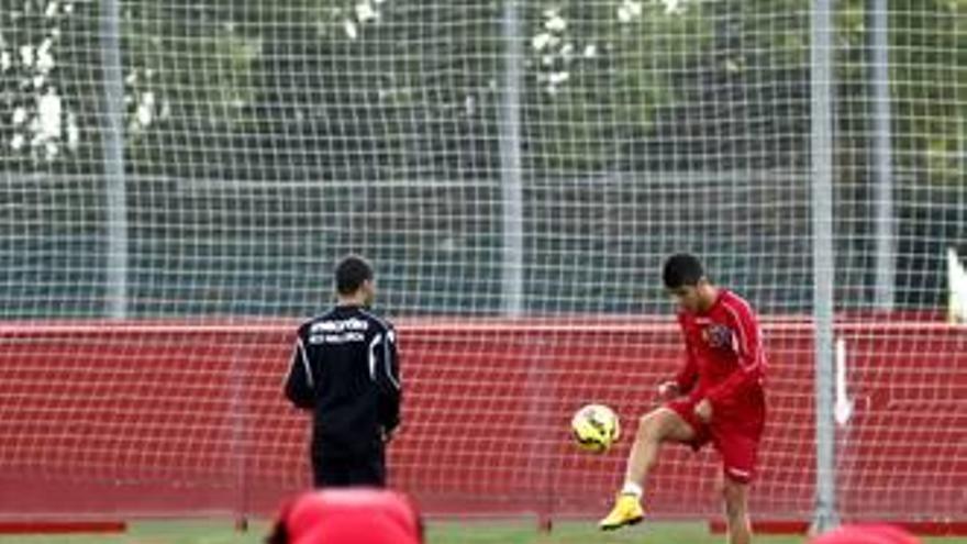 Marco Asensio hace toques con el balón mientras sus compañeros realizan ejercicios.