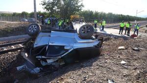 Un coche volcado y destrozado tras el impacto de un tren, en Alcolea.