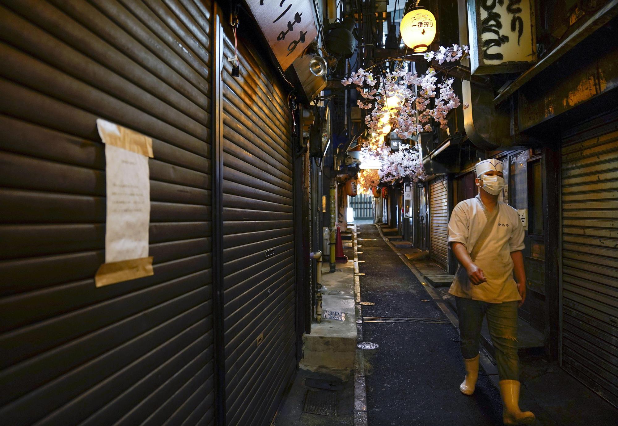 Un trabajador de un restaurante pasea por una zona de hostelería cerrada en Tokio