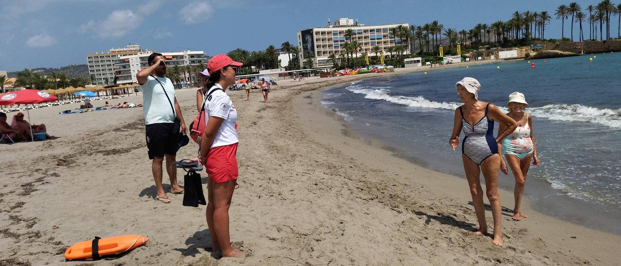 Unes banyistes pregunten a una de les socorristes de Creu Roja de la platja de l’Arenal