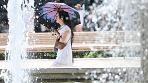 Una mujer se protege de la ola de calor en Milán.