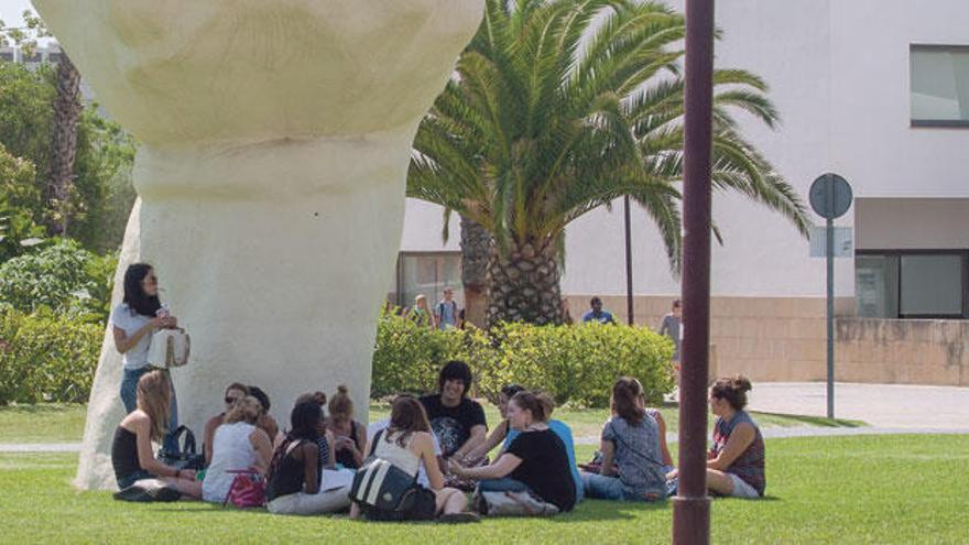 Estudiantes junto a la escultura más emblemática de la Universidad de Alicante.