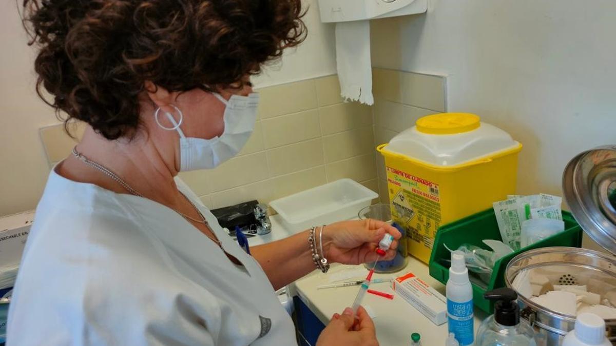 Una mujer sanitaria prepara una vacuna.