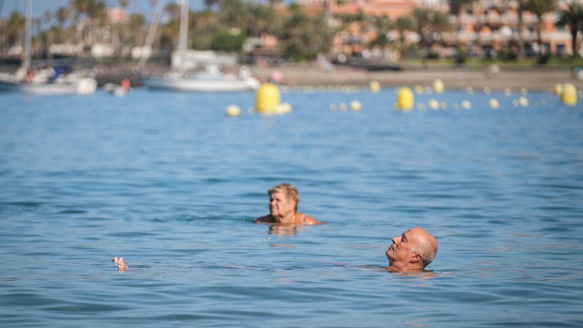 Dos turistas se dan un baño en la playa de Los Cristianos, al sur de Tenerife.