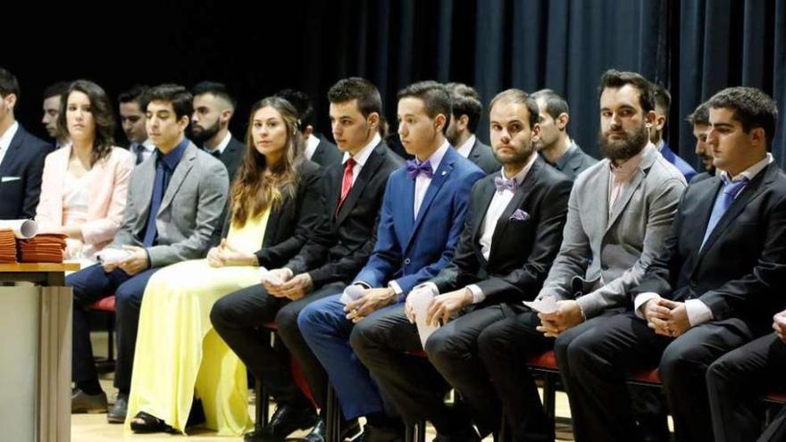 Los ingenieros, en el escenario, escuchan los discursos de sus profesores.