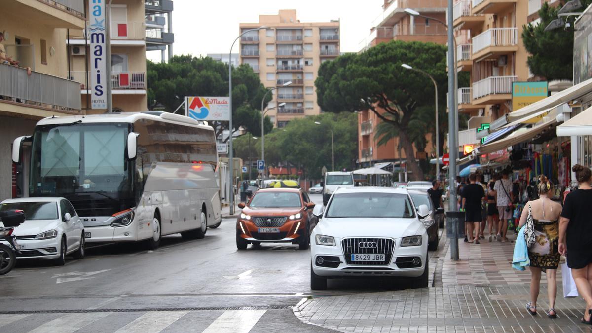 L&#039;avinguda de la Vila de Madrid de Blanes amb un autobús de turistes aparcat en un hotel, un cotxe circulant i vianants passejant