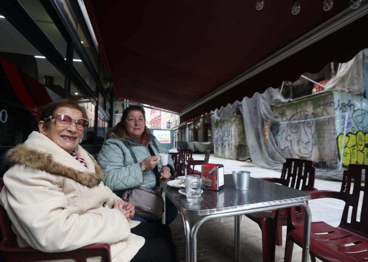 Por la izquierda, Carmen López y Leonor Gato, ayer, en una terraza de la calle Santa Lucía con el edificio del bar Pío detrás. | Luisma Murias