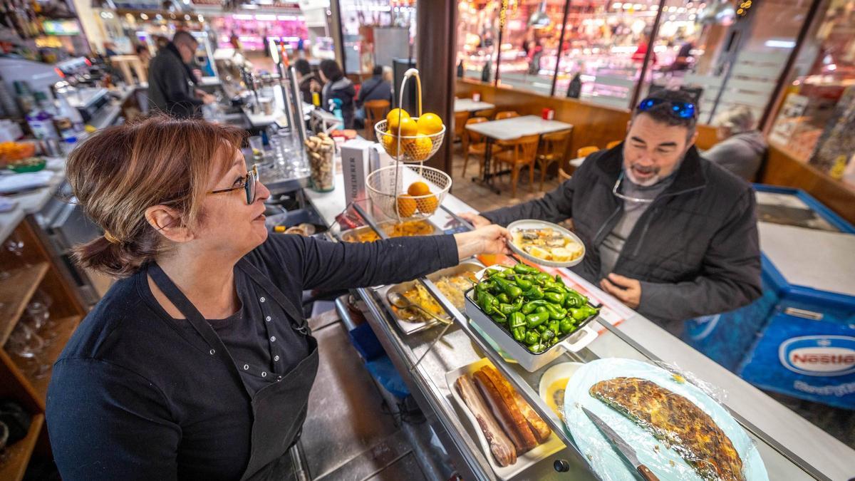 Mimi Sánchez Mercadé sirve un plato a un cliente en la barra del Bar del Mercat, en el Mercat del Centre de Vilanova i la Geltrú.