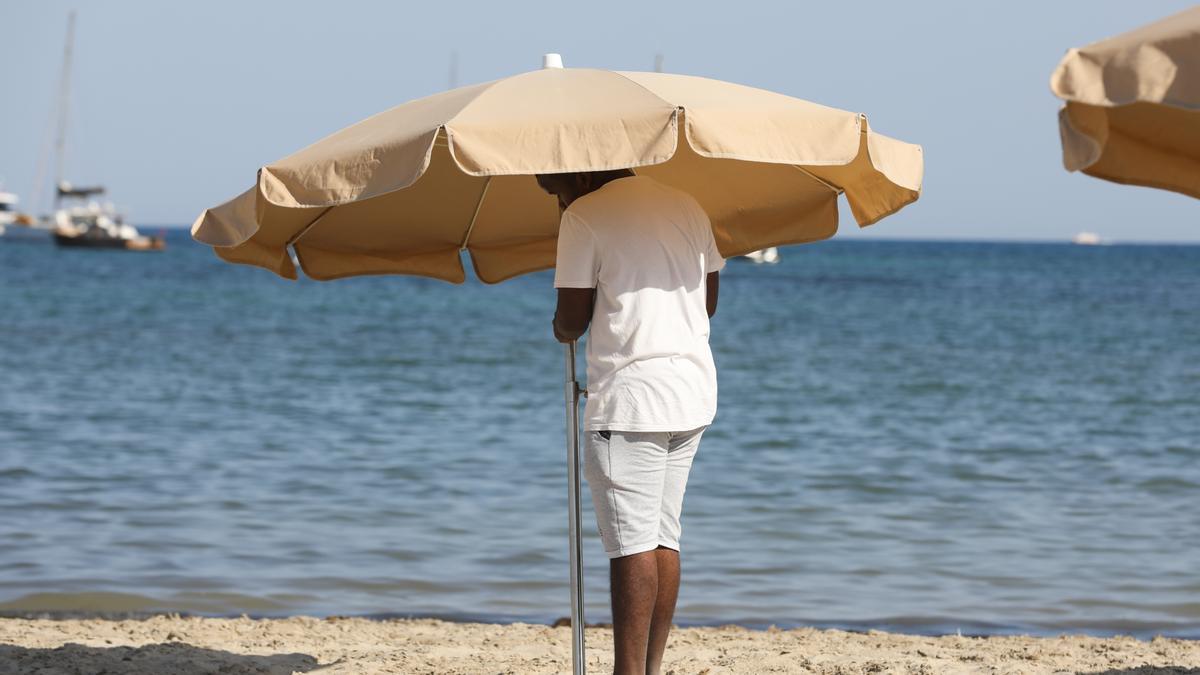 Un hombre instala una sombrilla en una playa de la isla.