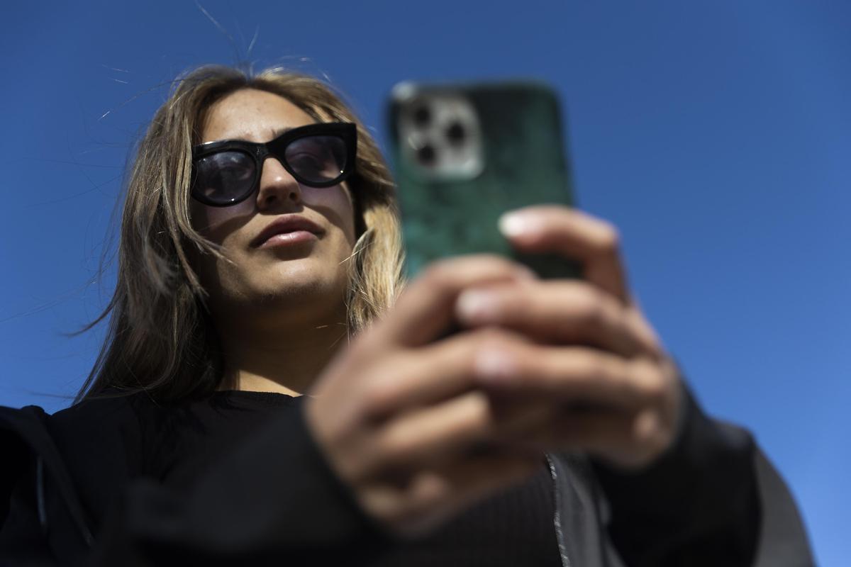 Una mujer consulta su teléfono móvil.