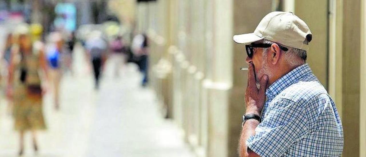 Un hombre fuma un cigarrillo en la calle Larios. | ÁLEX ZEA