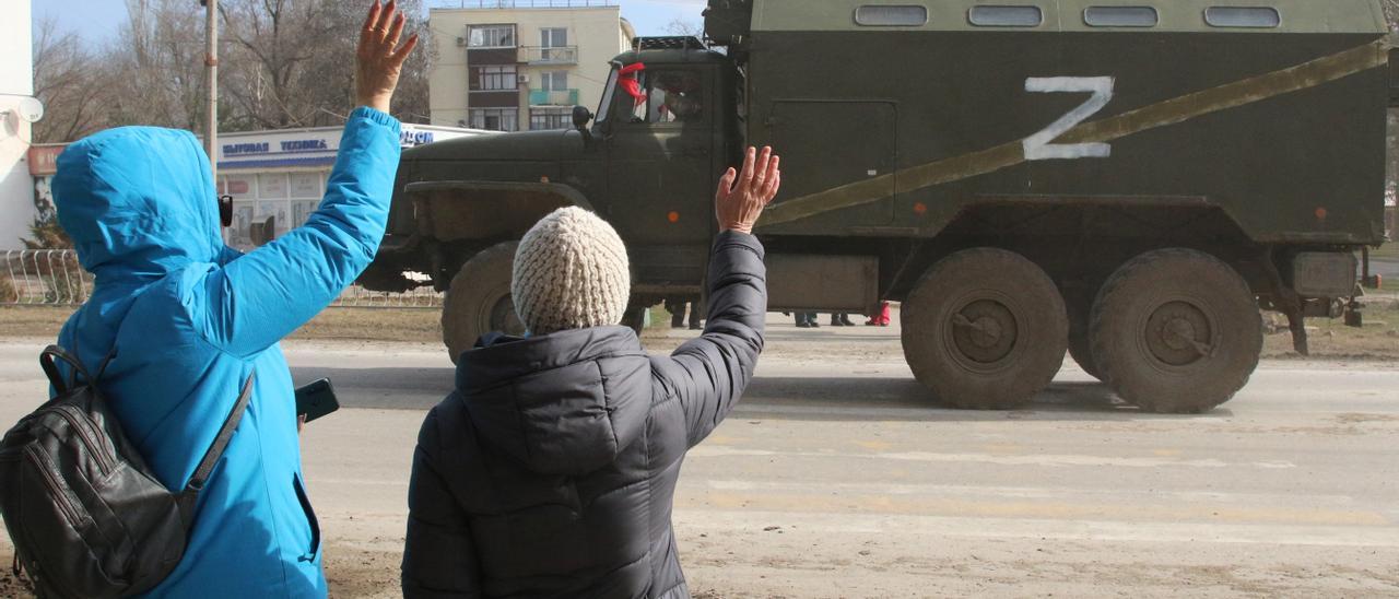 Dos niños saludan a un vehículo militar en Ucrana.