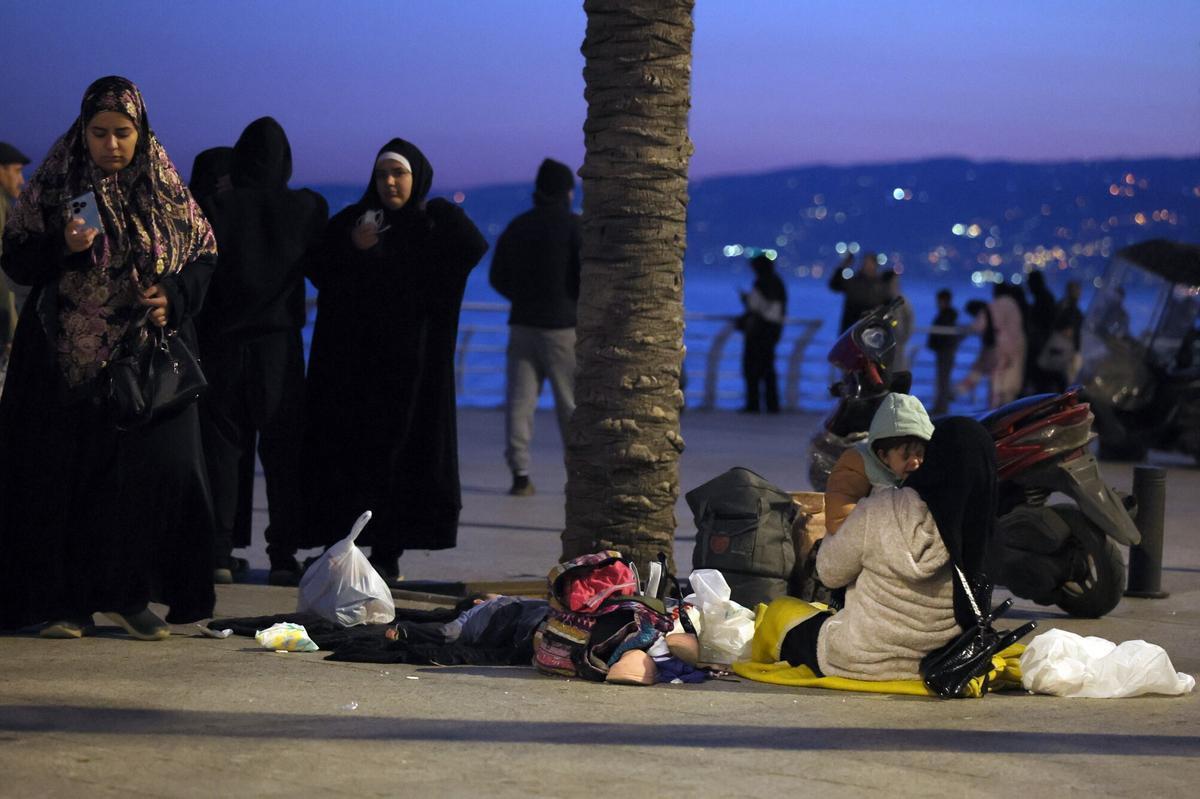Residentes desplazados del suburbio sur de Beirut aguardan se sientan en el suelo en el paseo marítimo de Al Manara en Beirut.
