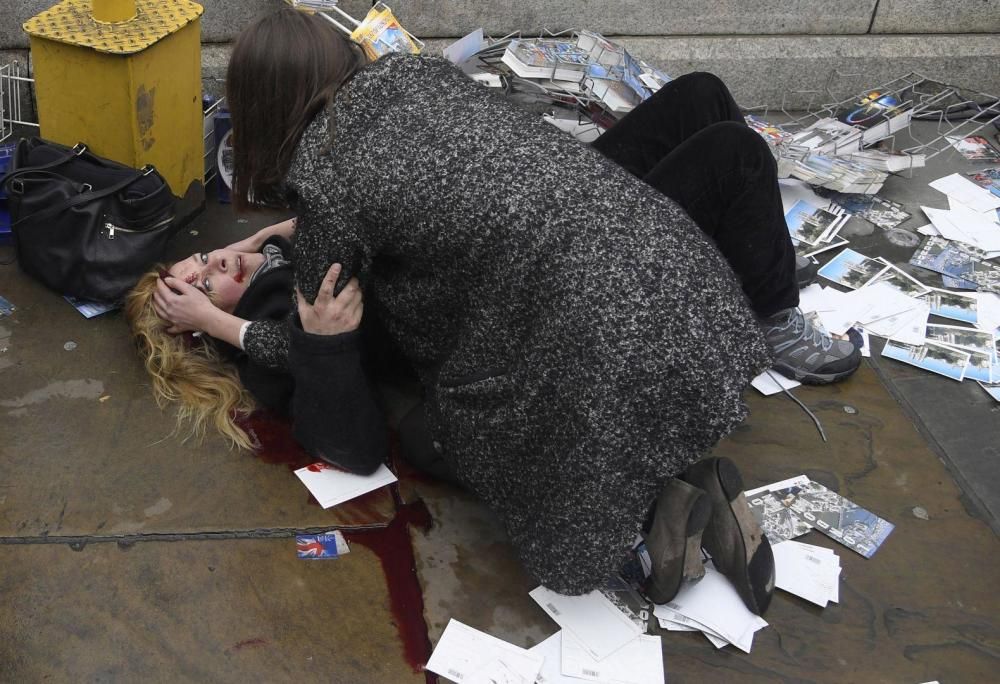 Un transeúnte consuela a una mujer herida después de que Khalid Masood condujera su automóvil contra peatones en el puente Westminster en Londres, Reino Unido, matando a cinco e hiriendo a otros muchos.