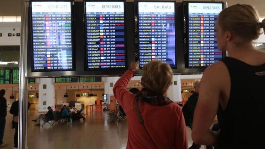 Una mujer señala un panel de control instalado en el aeropuerto de Málaga y que marca numerosas cancelaciones.