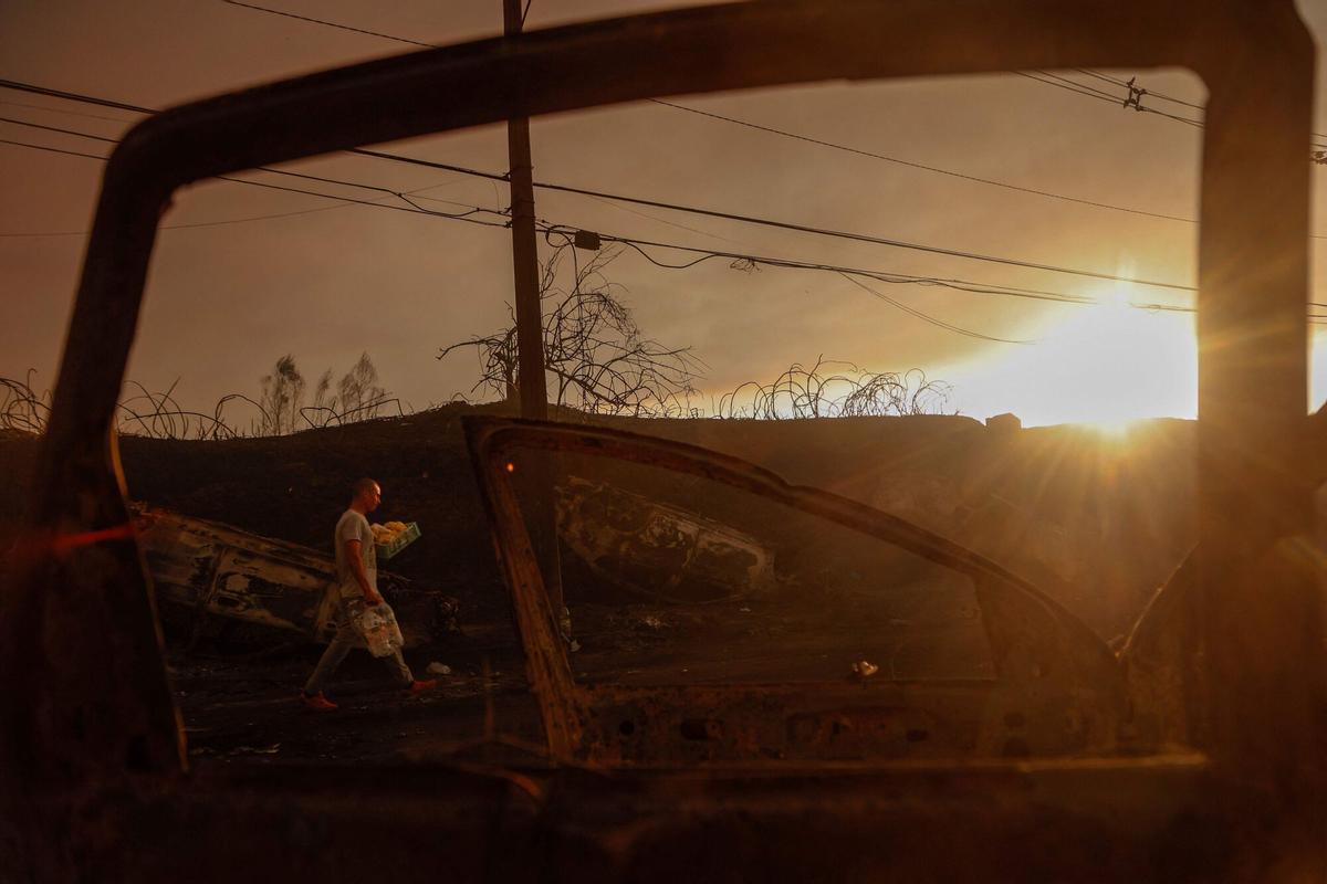 Un hombre lleva agua entre los coches quemados después de un incendio forestal en Concepción, Chile, el 18 de enero de 2026.