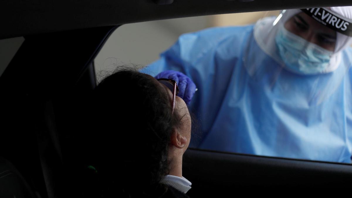 Una sanitaria toma una muestra a una joven en el interior de un coche