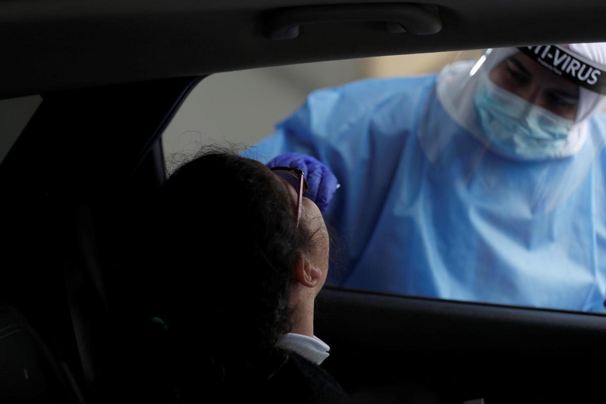 Una sanitaria toma una muestra a una joven en el interior de un coche