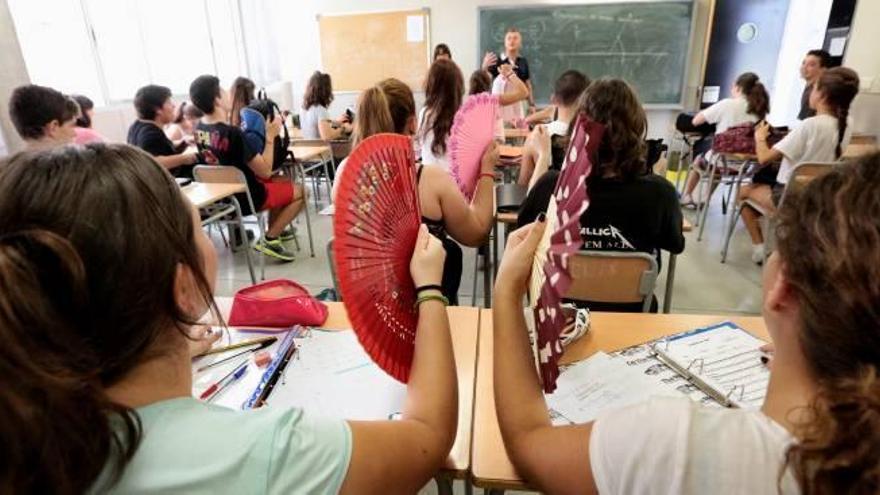 Alumnas de un instituto de Benidorm se dan aire con abanicos, mientras escuchan la clase, para poder aguantar el calor.