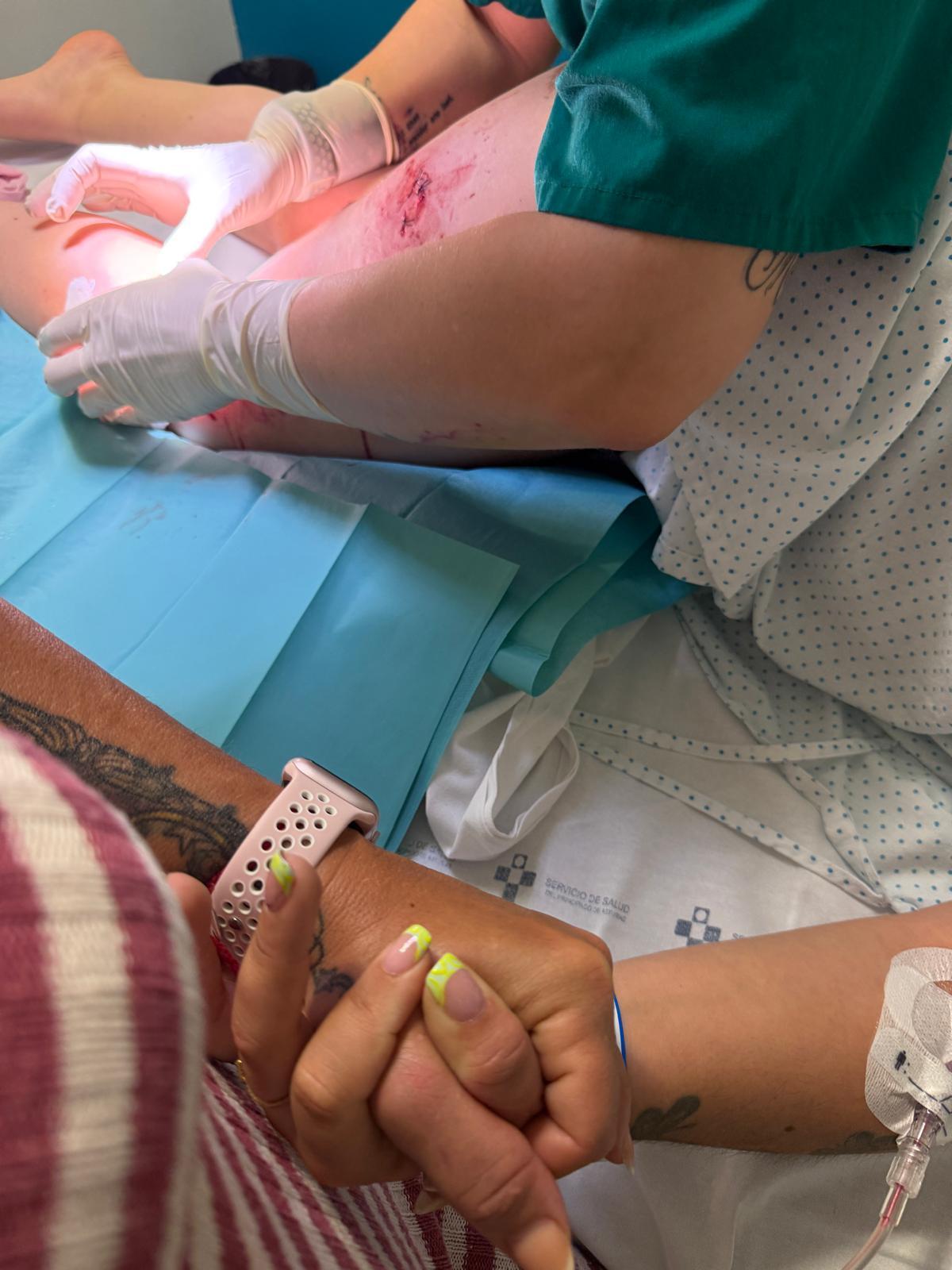 M. R. sostiene la mano de N.G. mientras una profesional sanitaria cura sus heridas tras el ataque del mastín.