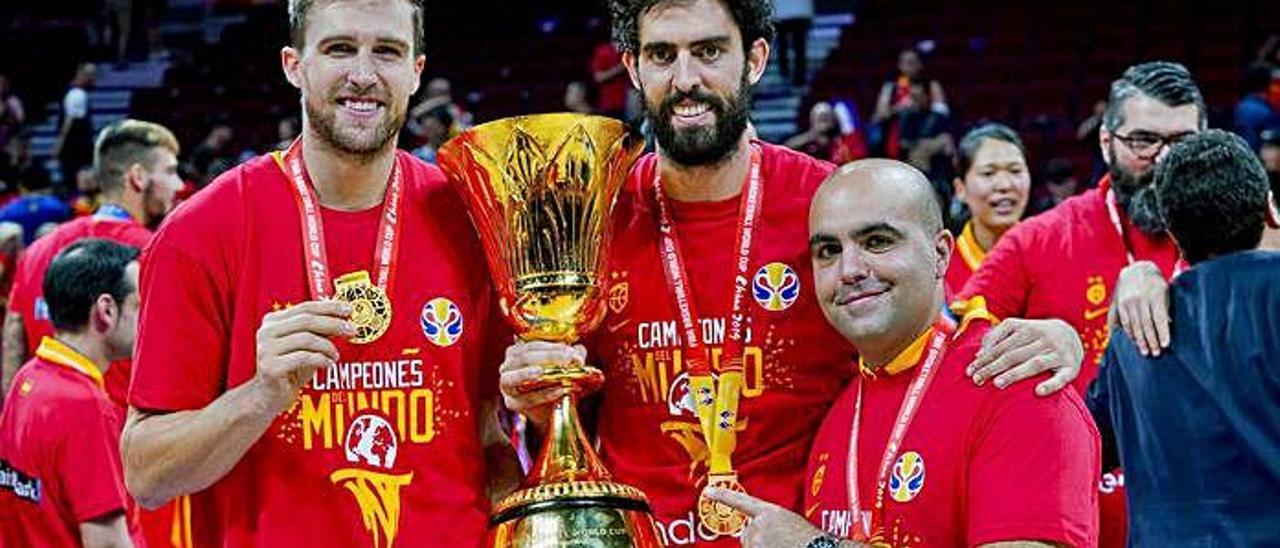 La representación del Granca en la selección española, los jugadores Javi Beirán -centro- y Xavi Rabaseda -izquierda-, y el técnico Víctor García -asistente de Scariolo-, posan con el trofeo y sus medallas al cuello.