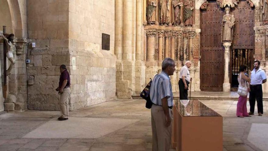 Varias personas observan detalles de la Colegiata junto al Pórtico de la Gloria.