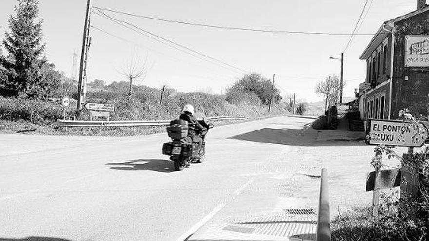 Una moto circula por la recta de Solís en el desvío a El Pontón, Taúxu y Rodiles.