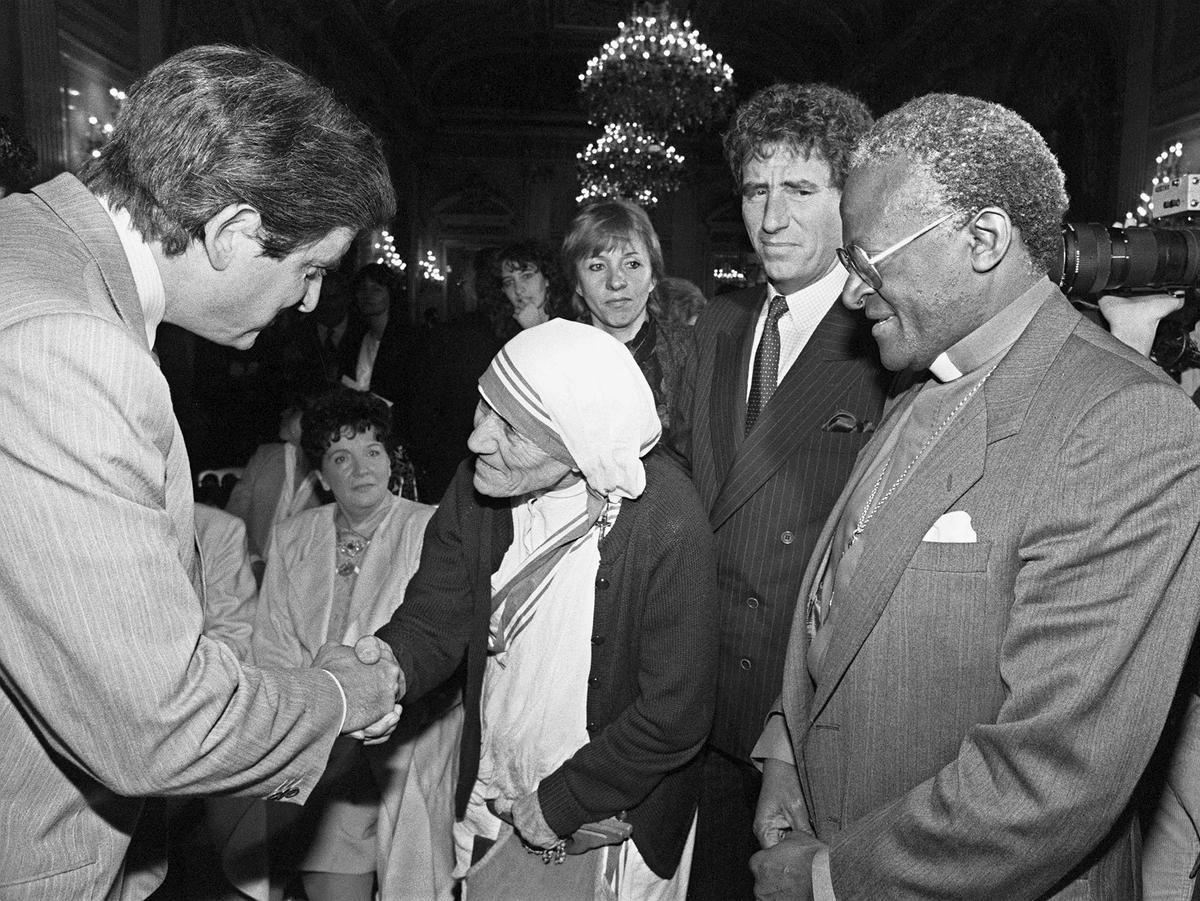 Desmond Tutu acompaña a la Madre Teresa de Calcuta, que saluda al ministro francés de Educación Nacional, Jean-Piere Chevenement, durante la celebración del coloquio ’Libertades y derechos humanos’, en París, el 30 de mayo de 1985.