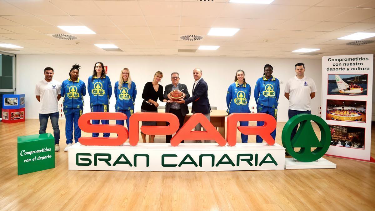 Domingo Díaz en el centro de la imagen sujeta un balón flanqueado a la izquierda por Dunia Pérez y a la derecha por José Lopez, acompañados de varias jugadoras y los entrenadores del primer equipo