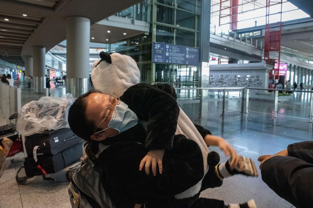 Un familiar abraza a un niño vestido con un disfraz de panda en la sala de llegadas de vuelos internacionales, el primer día en que se levantan oficialmente los requisitos de cuarentena para las llegadas internacionales.